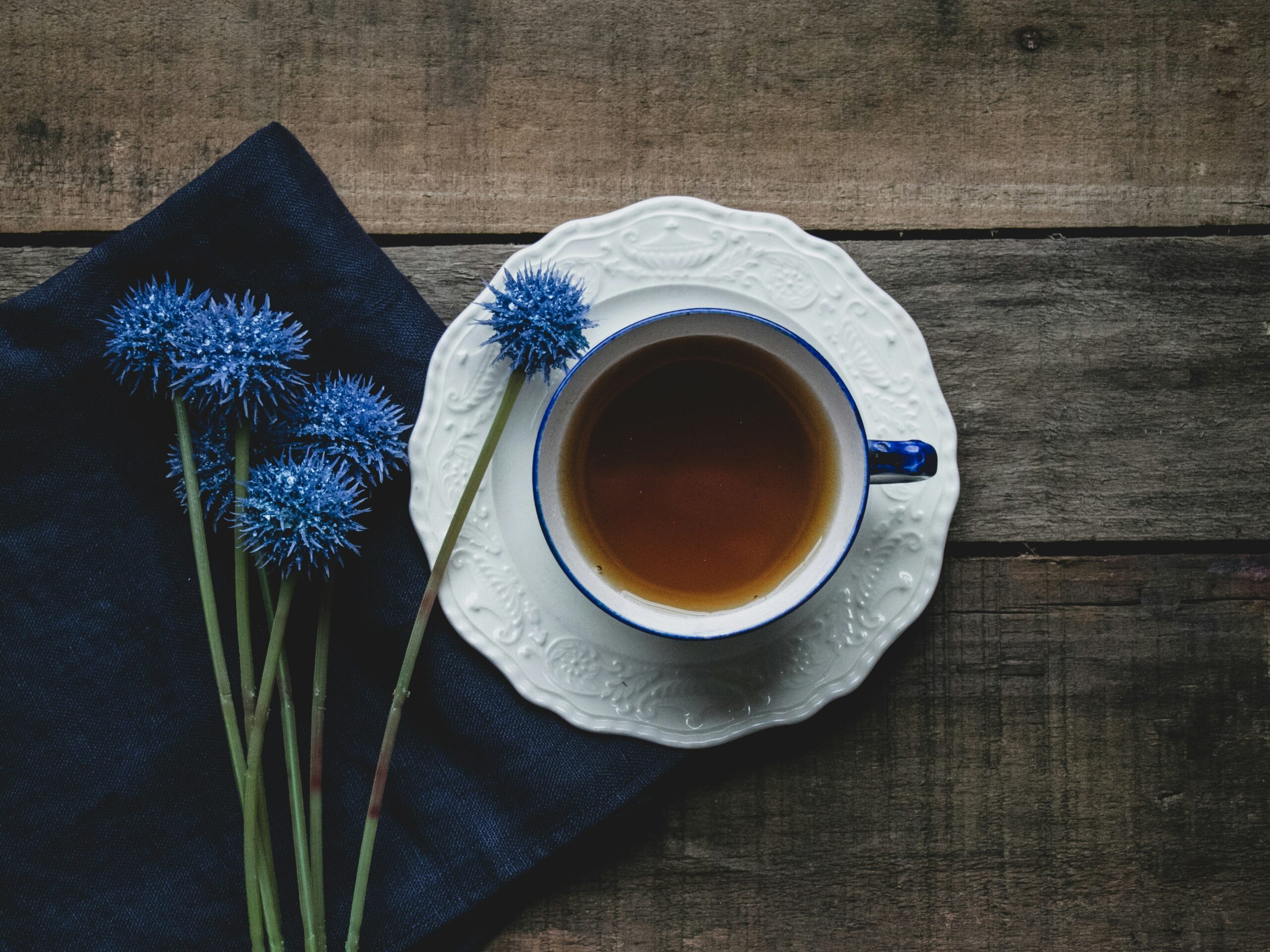Ayurveda Tipps — Eine Tasse Tee mit blauen Distelblüten auf Holztisch